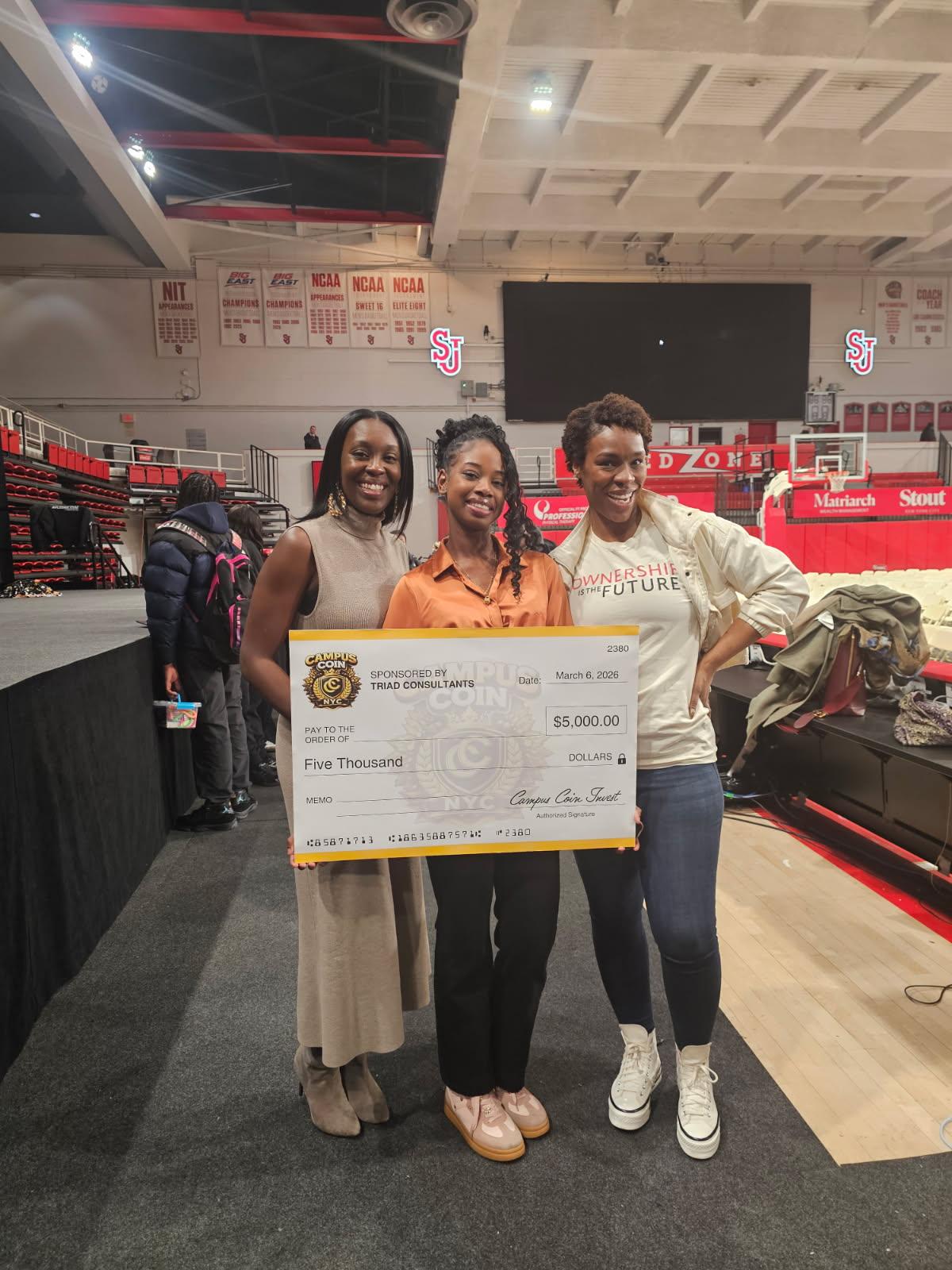 Malia Marcello appears in this photograph: three people pose with a $5,000 Campus Coin NYC check at St. John’s University